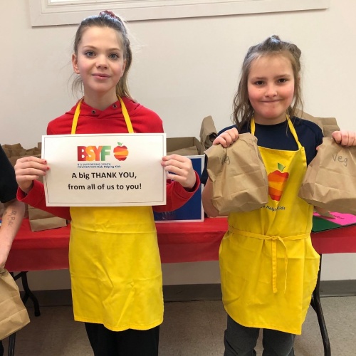 Two students holding bagged lunches